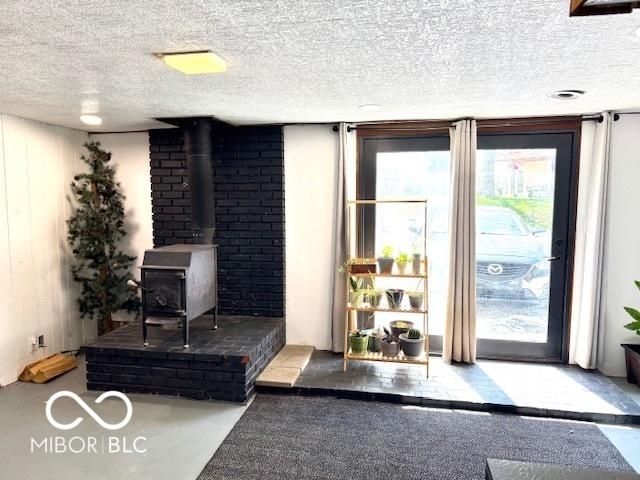 living area featuring a wood stove and a textured ceiling