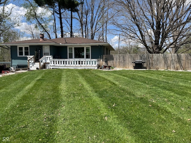 exterior space featuring fence, a chimney, and a lawn