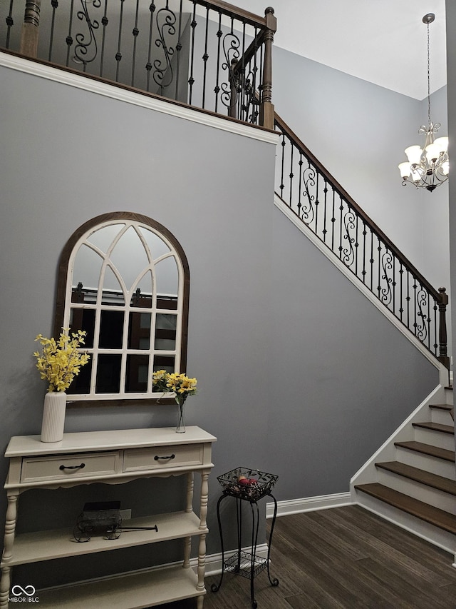 staircase featuring baseboards, wood finished floors, and a chandelier
