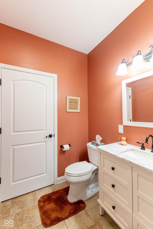 half bathroom with vanity, baseboards, and toilet