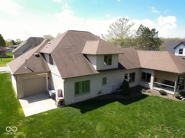 back of property with a garage, concrete driveway, a yard, and brick siding