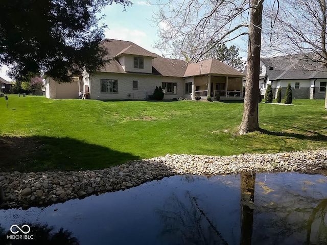 rear view of house featuring a yard and a sunroom