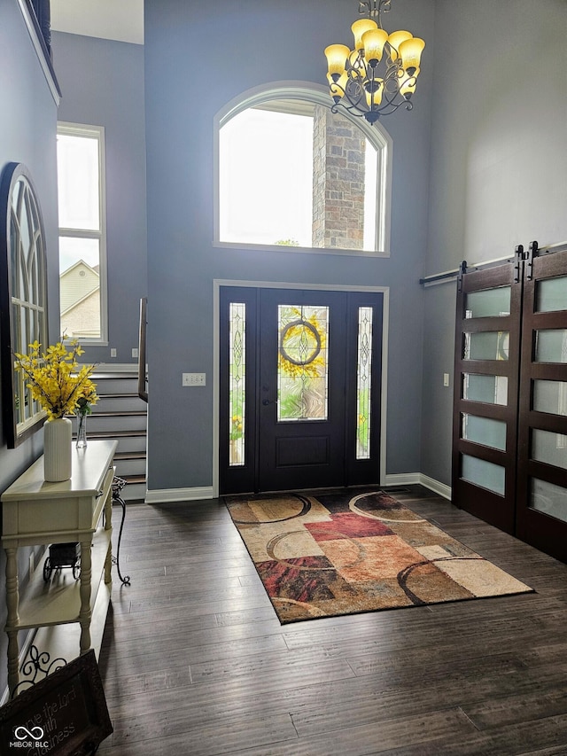 entryway with wood finished floors, baseboards, a high ceiling, and a notable chandelier
