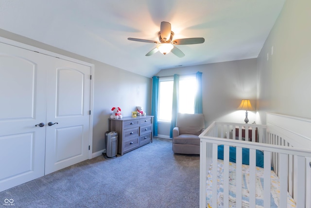 bedroom featuring a ceiling fan, a crib, a closet, lofted ceiling, and carpet