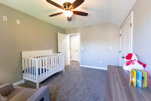 carpeted bedroom featuring visible vents, baseboards, a crib, a ceiling fan, and vaulted ceiling