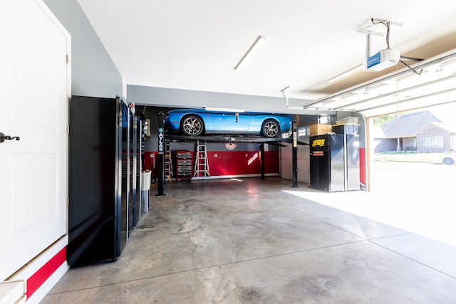 garage featuring freestanding refrigerator and a garage door opener