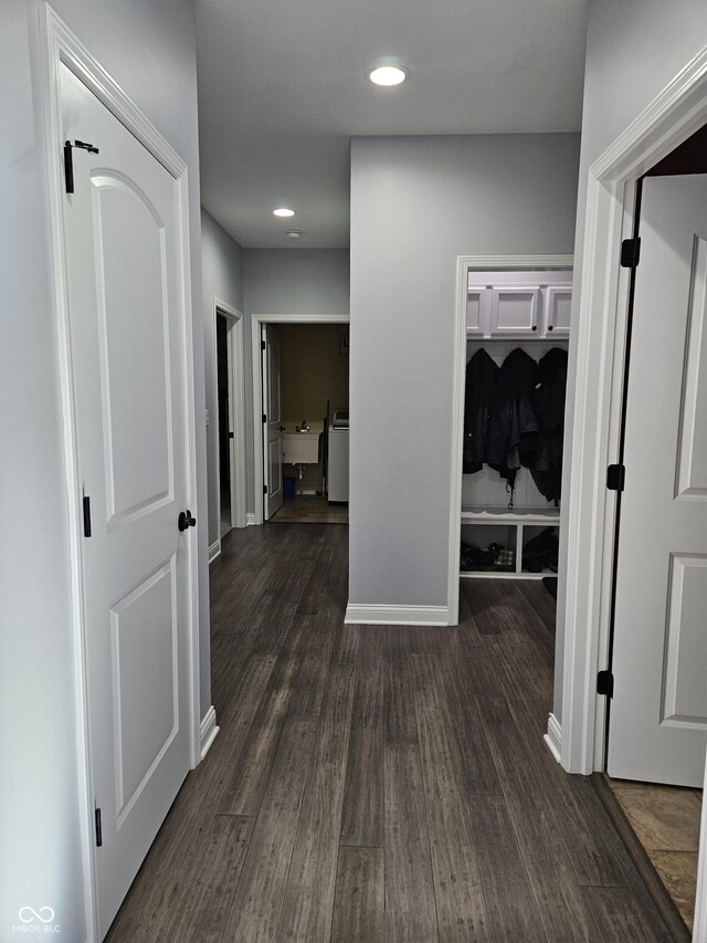 hallway featuring dark wood-type flooring, a sink, baseboards, and washer / clothes dryer