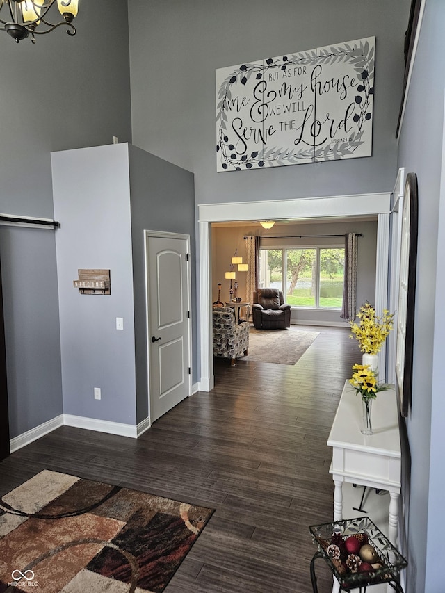 entrance foyer featuring an inviting chandelier, baseboards, wood finished floors, and a towering ceiling