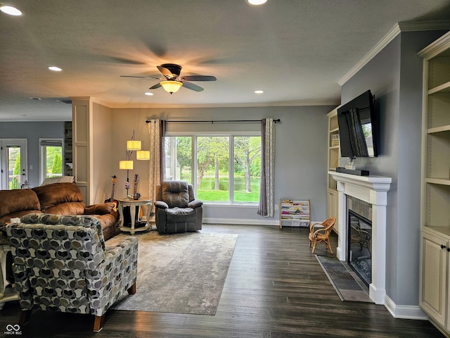 living area featuring a fireplace with flush hearth, a ceiling fan, dark wood-type flooring, and a wealth of natural light