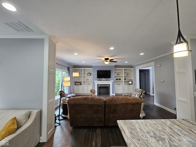 living area with visible vents, ornamental molding, dark wood-style flooring, a fireplace, and ceiling fan