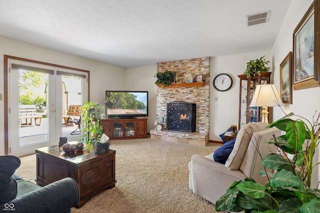 carpeted living room with french doors, a brick fireplace, a textured ceiling, and visible vents