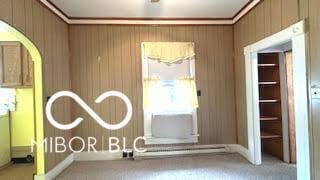 interior space with carpet flooring, arched walkways, wood walls, and ornamental molding