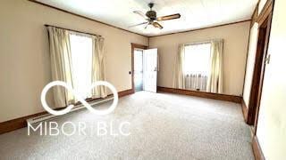 unfurnished room featuring baseboards, ceiling fan, carpet flooring, and a wealth of natural light