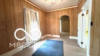 exercise room featuring baseboards, ceiling fan, ornamental molding, and wood walls