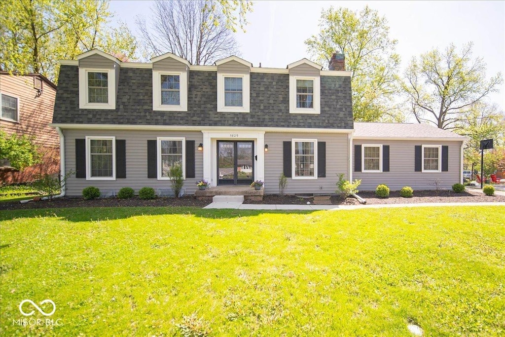 dutch colonial with a front lawn, a chimney, french doors, and roof with shingles