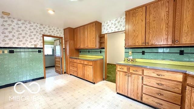 kitchen featuring open shelves, wainscoting, brown cabinetry, wallpapered walls, and light floors