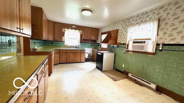 kitchen with wallpapered walls, a wainscoted wall, cooling unit, a baseboard heating unit, and brown cabinets
