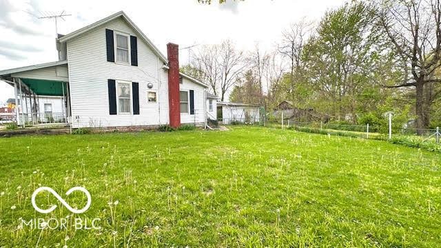 back of house with fence, a chimney, and a yard