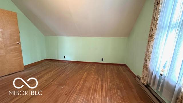 bonus room with baseboards, lofted ceiling, wood finished floors, and baseboard heating