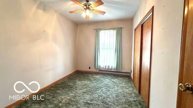 unfurnished bedroom featuring a closet, baseboards, carpet, and a baseboard heating unit