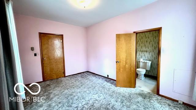 unfurnished bedroom featuring ensuite bathroom and carpet flooring