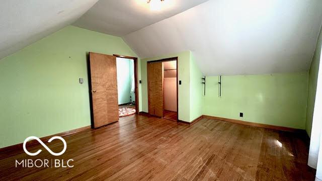 bonus room with baseboards, vaulted ceiling, and wood finished floors