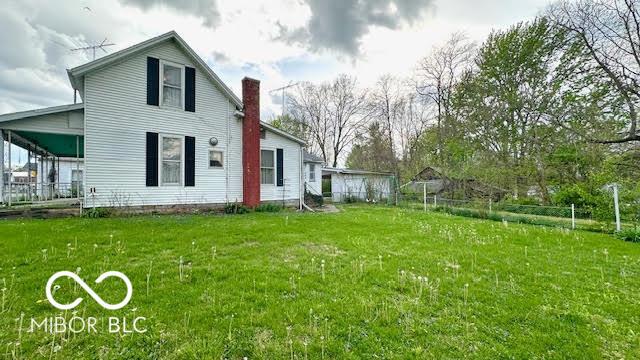 back of property featuring a lawn, fence, and a chimney