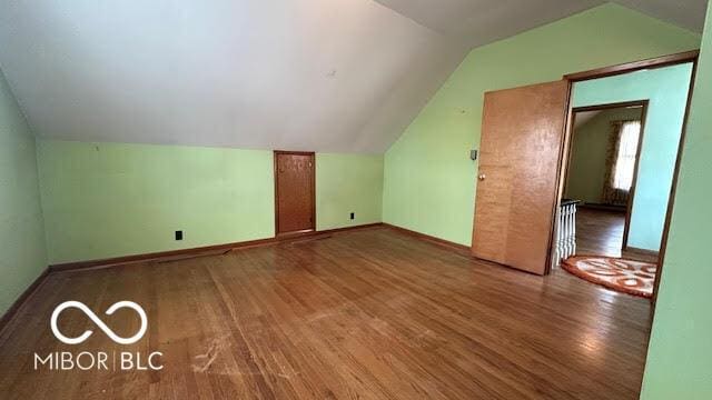 additional living space with baseboards, wood finished floors, and lofted ceiling