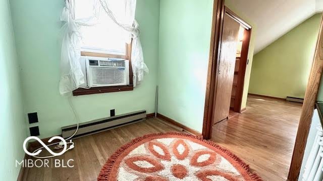 additional living space featuring wood finished floors, lofted ceiling, baseboard heating, a baseboard heating unit, and cooling unit