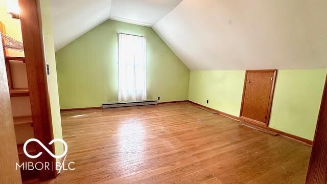 additional living space with wood finished floors, baseboards, and a baseboard heating unit