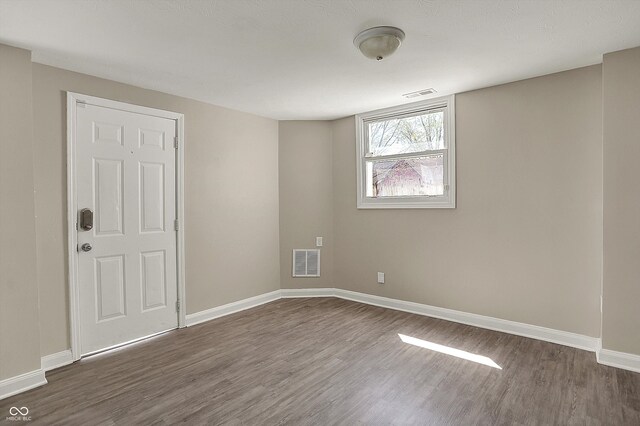 unfurnished room featuring visible vents, baseboards, and dark wood finished floors