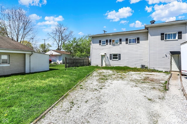 back of house featuring fence and a lawn