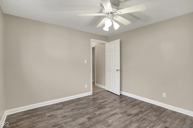 unfurnished room with dark wood-type flooring, ceiling fan, and baseboards