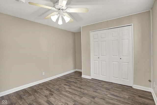 unfurnished bedroom with dark wood-type flooring, ceiling fan, baseboards, and a closet