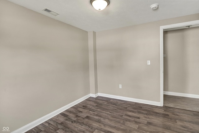 spare room featuring visible vents, dark wood-style flooring, and baseboards
