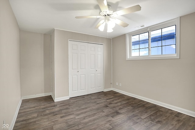 unfurnished bedroom with dark wood-style floors, a closet, ceiling fan, visible vents, and baseboards