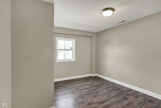 spare room featuring baseboards, visible vents, and dark wood-type flooring