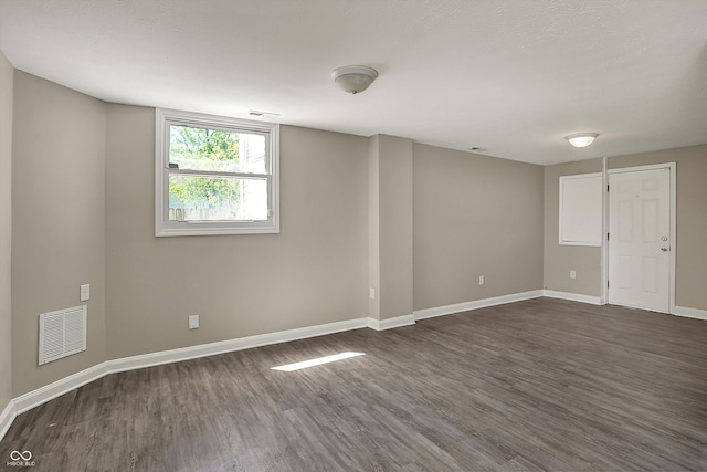 unfurnished room with dark wood finished floors, visible vents, and baseboards