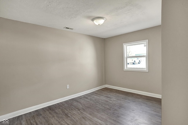 unfurnished room featuring baseboards, visible vents, a textured ceiling, and dark wood-style flooring