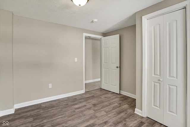 unfurnished bedroom featuring dark wood-style flooring, baseboards, and a closet