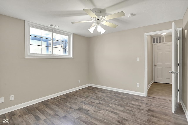 empty room featuring dark wood finished floors, baseboards, visible vents, and a ceiling fan
