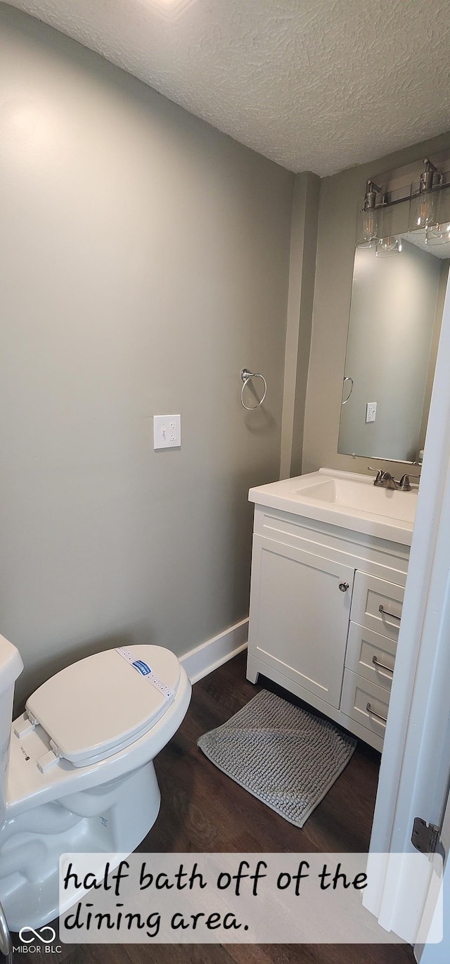 bathroom with vanity, a textured ceiling, toilet, and wood finished floors
