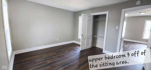unfurnished bedroom featuring a textured ceiling, dark wood-type flooring, and baseboards