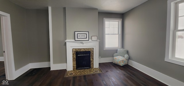 unfurnished living room with a wealth of natural light, baseboards, a fireplace with flush hearth, and wood finished floors