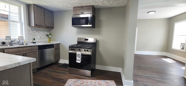 kitchen featuring a sink, stainless steel appliances, a textured ceiling, and dark wood-type flooring