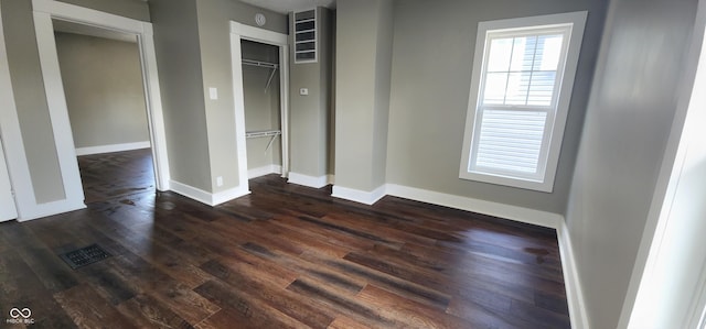 unfurnished bedroom featuring a closet, dark wood finished floors, visible vents, and baseboards