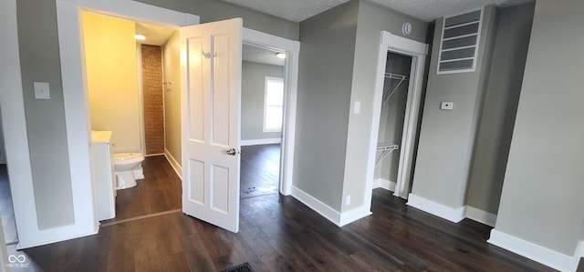 interior space featuring baseboards, a textured ceiling, and dark wood-type flooring