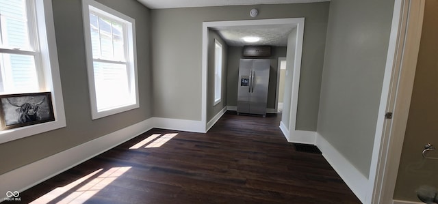 hallway with baseboards, visible vents, and dark wood finished floors