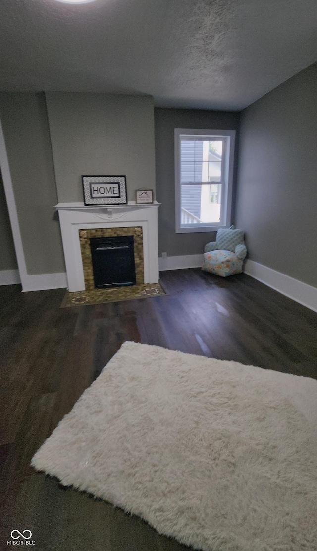 living room with a tile fireplace, baseboards, and wood finished floors