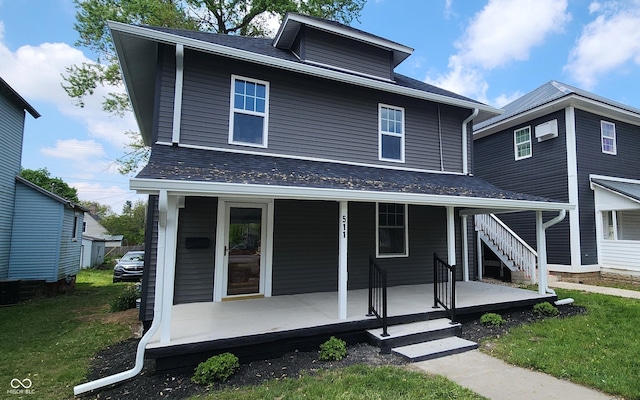 american foursquare style home with a front yard, roof with shingles, and covered porch